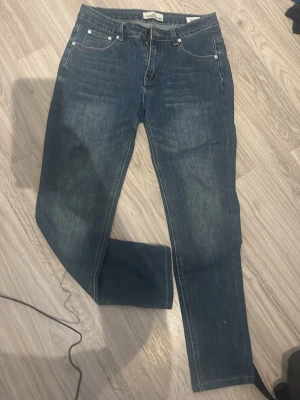 Blå raka jeans Stone island - Säljer ett par klassiska blå jeans med rak passform och fem fickor. Jeansen har en snygg tvättad look och silverfärgade nitar. Perfekta till vardags för en avslappnad stil. Materialet är denim i bomull. Stone island ❓saknar badge