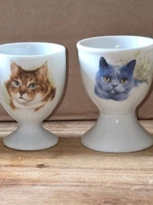 Äggkoppar med katt- och hundmotiv, 6 st - Fyra vita äggkoppar i porslin med färgglada motiv av katter och hundar på framsidan. Två koppar har kattmotiv och två har hundmotiv, alla med realistiska illustrationer. Perfekt för djurälskare som vill ha något unikt till frukostbordet.