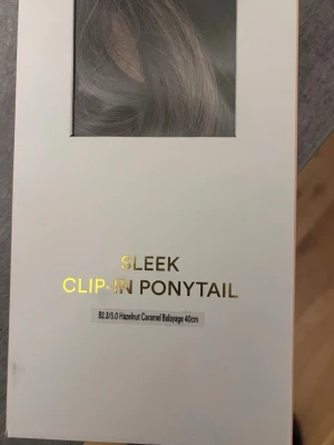 Sleek clip-in hästsvans 40cm - Snygg clip-in hästsvans i färgen hazelnut caramel balayage, 40 cm lång. Ger ett naturligt och fylligt intryck med mjuka karamellbruna toner och en sleek finish. Perfekt för dig som vill ha längre och tjockare hår på nolltid.