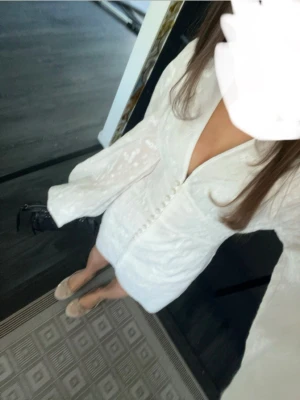 Vit kort klänning med v-ringning - Super fin klänning från adoore som är nästintill helt ny, använd bara 2 gånger på grund av att den blivit för liten. Den är vit med blommor på och har en fin V-ringning💕
