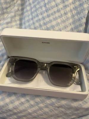 Grå CHIMI solglasögon i transparent acetat - Snygga solglasögon från CHIMI med transparent grå båge i fyrkantig form. Glasen är mörka och bågarna är tillverkade i acetat. Perfekta för att lyfta din stil med en modern touch. Använda några få gånger. Paketet skickas iväg direkt efter köp för snabb leverans! 📦🌸