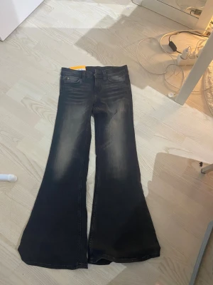 Cheap monday  - Säljer ett par gråa jeans med utsvängda ben och snygg tvätt. Klassisk femficksmodell med hög midja och slitningar på framsidan för en cool look. Perfekta för dig som gillar retrostil och vill sticka ut lite extra.