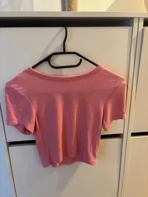 Rosa croppad topp med kort ärm - Söt rosa croppad topp med korta ärmar och rund halsringning. Tillverkad i mjukt material som känns skönt mot huden. Perfekt för dig som gillar en enkel men trendig stil.
