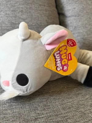 NY! ZURU Hug A Lumps 1,5kg Get gosedjur - ZURU Hug A Lumps gosedjur i form av en get. Gosedjuret är grått och vitt med svarta hovar och rosa insida av öronen. Etiketten sitter kvar på gosedjuret.  Vikt 1,5kg!  Ny i förpackning!