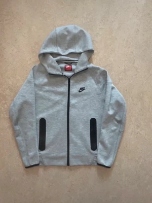 Grå hoodie från Nike med dragkedja - Snygg grå hoodie från Nike med svart dragkedja och svarta detaljer vid fickorna.                                                 —————SKICKA GÄRNA BUD————