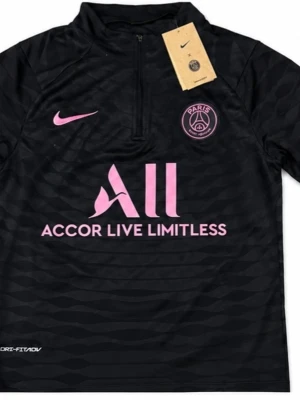 Svart PSG träningströja med rosa detaljer - Snygg svart träningströja från PSG med halv dragkedja och rosa loggor. Tillverkad i ett lätt och snabbtorkande funktionsmaterial med diskret mönster. Perfekt för fotbollsträning eller gymmet. Det är S, men det är lite oversized så det passar för både S och M.