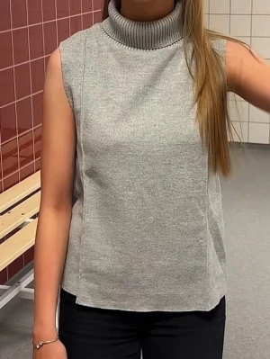 Grå ärmlös stickad poloväst - Säljer en stilren grå stickad väst med hög polokrage och ärmlös design. Perfekt att bära över en skjorta eller t-shirt för en trendig lager-på-lager-look. Materialet är mjukt och stretchigt, vilket gör den bekväm att ha på sig hela dagen.