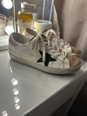 63% off på Golden Goose - Köpte dessa snygga vita sneakers från Golden Goose med rosa mockadetaljer på tån och svart stjärna på sidan för nästan 7 tusen kronor denna våren och säljer dom nu efter några månaders användning. Jag är öppen för alla frågor, även prissänkningar!💕