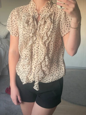 Beige prickig blus med volanger - Söt beige prickig blus! Tillverkad i ett tunt, lätt och transparent material. Perfekt till alla årstider och går att både klä upp och ned!💕