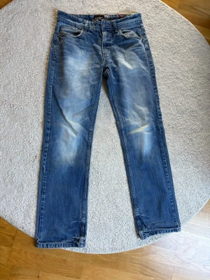 Blå raka jeans med slitningar - Jeansen har klassisk femficksmodell och normal midja. Materialet är denim i bomull och färgen är tvättad blå med ljusare partier för en cool look. W