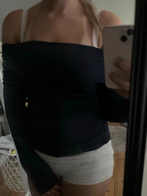 Mörkblå offshoulder långärmad topp - Snygg mörkblå offshoulder topp med långa ärmar. Toppen har en åtsittande passform och är perfekt för dig som vill ha en stilren och enkel look. Tillverkad i mjukt material som känns skönt mot huden.