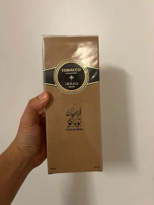 Arabian Tobacco | Extrait De Parfum | by Ibrahim Al Qurashi - Arabian Tobacco | Extrait De Parfum | by Ibrahim Al Qurashi. Parfymen kommer i en stilren, rektangulär förpackning i brunt med svarta och guldfärgade detaljer. Flaskan rymmer 100 ml och har en exklusiv känsla med elegant design och arabiska inslag.
