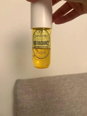 Sol de Janeiro Rio Radiance mist - Fräsch doftmist från Sol de Janeiro i varianten Rio Radiance. Flaskan är genomskinlig med gul vätska och har en vit kork. Doften har inslag av solvarm tuberos och kokos. Perfekt för dig som vill ha en tropisk och somrig parfym.