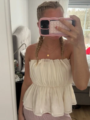  tubetopp/ fest topp - Säljer en superfin vit axelbandslös topp med volanger och lätt rynkad struktur. Perfekt till alla typer av tillfällen!! SLUTSÅLD!!