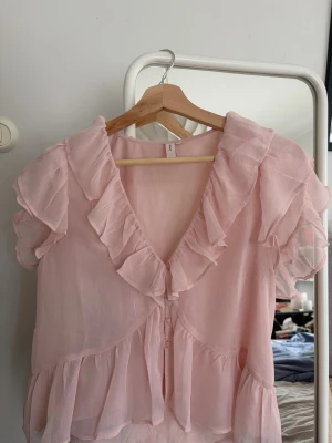 Ljusrosa volangblus  - Supersöt ljusrosa blus med v-ringning och volangdetaljer, använd 1 gång!