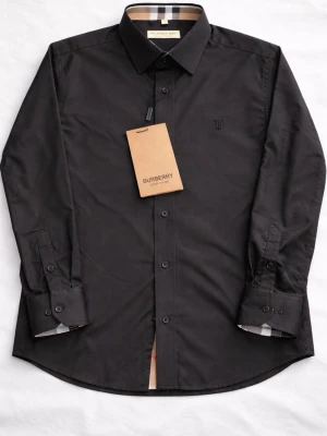 Svart skjorta från Burberry - Snygg svart skjorta från Burberry med klassiskt rutigt mönster på insidan av kragen och manschetterna. Skjortan har knappar framtill och en diskret broderad logga på bröstet. Tillverkad i ett mjukt och glansigt material som känns lyxigt.