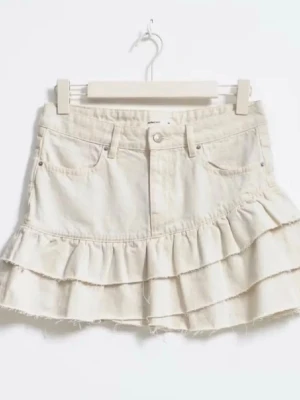 Vit volangkjol i denim - Supersöt kort kjol i vit denim med två volanglager och råa kanter. Kjolen har klassiska jeansfickor fram och bak samt knapp och dragkedja i midjan. Perfekt för dig som vill ha en trendig och avslappnad look.