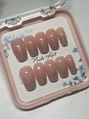 Handgjorda Nude glitter press-on naglar - Snygga press-on naglar i nude med silverglittrig ombre-effekt. Naglarna har en mjuk fyrkantig form och kommer i en söt ask med blommönster. Perfekt för dig som vill ha en elegant och trendig look utan att gå till salong.