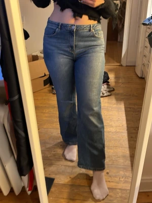 Blå raka jeans med hög midja - Säljer ett par klassiska blå jeans med hög midja och raka ben. Jeansen har fem fickor, bälteshällor och stängs med knapp och dragkedja. Perfekta till vardags och passar till det mesta. Materialet är kraftig denim i bomull.
