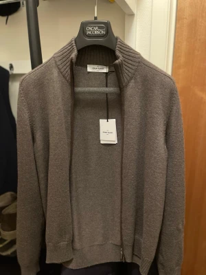 Gran Sasso cardigan 48 - Grå/Beige merinoull cardigan från Gran Sasso med mocka patches på armbågarna. Använd fåtalet gånger.