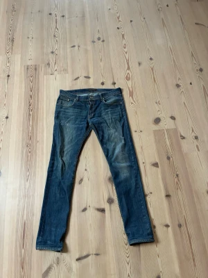 Blå slim fit jeans från Nudie Jeans - Säljer ett par blå slim fit jeans från Nudie Jeans. Storlek waist 33 length 34. Gylf dragkedjan är rätt seg men annars är dom fläckfria. Blivit för tajta på mig så därför jag säljer.