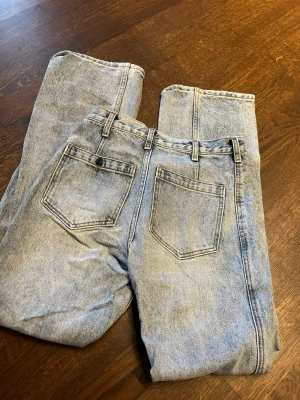 Ljusblå raka jeans i vintage-stil - Säljer ett par ljusblå jeans med rak passform och klassisk femficksdesign. De är mid- high straight baggy. Den har inga lappar så vet inte märke och storlek men på bild 2 och 3 syns måtten.  
