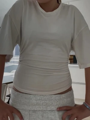 Vit croppad t-shirt med loose fit - Säljer en enkel och stilren vit t-shirt med croppad passform och loose fit. T-shirten har korta ärmar och rund halsringning. Perfekt till jeans eller shorts för en avslappnad look.