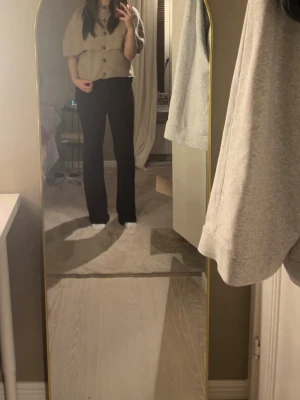  stickad poncho- Gina tricot - Mysig beige stickad poncho med stora knappar framtill och korta ärmar. Lös passform och ribbad krage. 