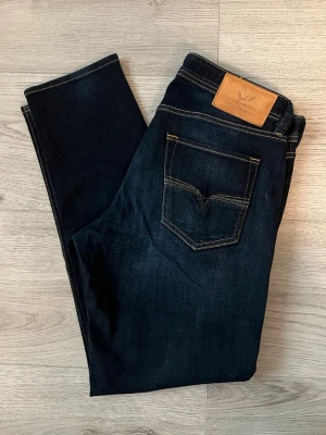 Mörkblå jeans från Diesel - Snygga raka mörkblå jeans från Diesel med klassisk femficksdesign. Jeansen har en läderpatch med logga bak i midjan och är tillverkade i stretchigt denim för extra komfort. 