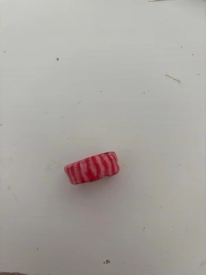 Rödrosa randig ring i lera - En cool ring i lera med röd och rosa randig design. Ringen har en rund form och känns lekfull och unik, perfekt för dig som vill sticka ut med dina accessoarer. Passar till dig som gillar färgglada detaljer.