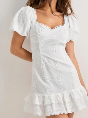 Vit Studentklänning - Supersöt vit kort klänning med puffärmar, broderade blommor och volangkant.  Aldrig använt, storlek 34 