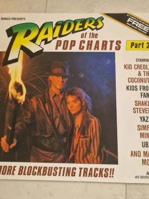 Ronco Raiders of the Pop Charts Part 2 vinylskiva - Ronco Raiders of the Pop Charts Part 2 vinylskiva. Samlingsalbum med poplåtar från olika artister, utgivet av Ronco. Omslaget visar låtlista med flera kända artister och spår på både sida ett och sida två. Lämplig för uppspelning på skivspelare som klarar LP-format.