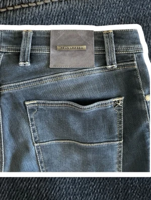 Tramarossa jeans - Snygga mörkblå jeans från Tramarossa med smal passform och klassisk femficksdesign. Jeansen har diskreta slitningar och kontrastsömmar samt en patch med logga bak i midjan. Tillverkade i mjukt denimtyg med stretch för extra komfort.