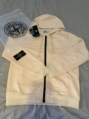 Beige hoodie från Stone Island - Säljer en skön och fin stone island tröja som har storlek M 🤩 jätte vacker och passar för sommaren och allt väder👍jätte fint material som passar för varmt väder. Passa på och köpa när det är fri frakt 📦. Säljer den pga behöver pengar för körkort. Hör av dig om du är intresserad😉 priset kan diskuteras👍