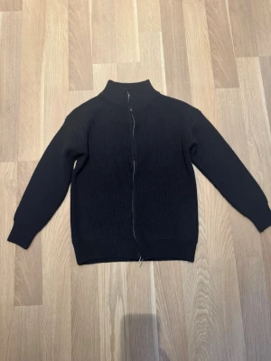 Svart zip hoodie - En stilren svar kofta med hög krage och dragkedja framtill. 