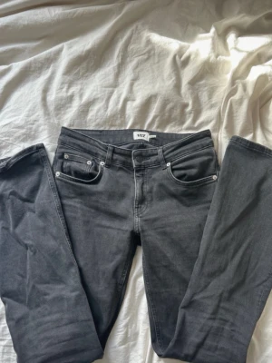 Grå/svarta low bootcut jeans från 157 - Snygga grå jeans från 157 med low bootcut-modell. Klassisk femficksdesign och silverfärgade nitar. Jeansen har låg midja och raka ben, perfekta för en avslappnad och trendig look. Materialet är mjukt denim som sitter skönt hela dagen.