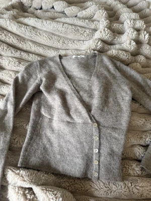 Mörk Begie kofta från Gina tricot - Mysig begie kofta från gina med v-ringning och långa ärmar. Koftan har en figurnära passform och stängs med fem vita knappar framtill. Tillverkad i mjukt stickat material som passar perfekt för lager på lager.