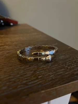 Silvrigt armband med nitar - Snyggt armband i silverfärgad metall med geometriska nitar runt hela bandet. Armbandet har en flexibel design och cool, edgy känsla som sticker ut. Perfekt för dig som gillar accessoarer med attityd och vill addera något extra till din stil.