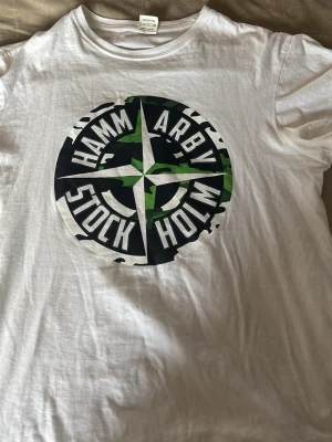 Hammarby T-Shirt - ”Hammarby Stockholm” T-shirt. 🧭Sparsamt använd och inga tecken på användning. Storleken är L men sitter som M/L