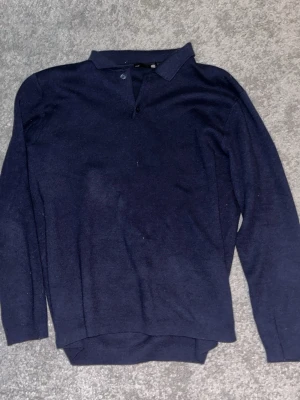 Mörkblå långärmad pikétröja - Mörkblå långärmad pikétröja med klassisk krage och knappslå framtill. Tröjan har en rak passform och är tillverkad i ett mjukt, tunt material som passar perfekt till jeans. Enkel och stilren design utan synliga loggor.