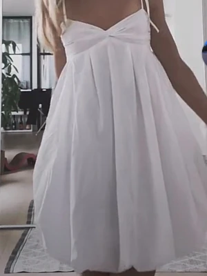 Vit sommar klänning  - Säljer en jätte fin sommarklänning med tunna axelband och v-ringad urringning. Klänningen har ett luftigt fall och veckade detaljer framtill som ger extra volym. 