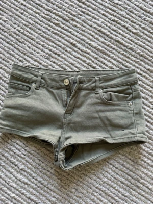 Gröna midwaist shorts med fickor - Snygga gröna shorts i midwaist-modell med klassisk femficksdesign och knapp- samt dragkedjestängning. Perfekta för varma dagar och har bälteshällor för extra stylingmöjligheter. Materialet känns mjukt och bekvämt.