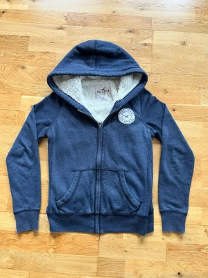 Vintage Hollister hoodie (y2k modell) - Säljer nu denna fodrade Hollister hoodien. Hoodien är i väldigt bra skick och ganska varm vilket är perfekt nu till våren. Storlek S och modellen på bilden är 173 och väger ca 60 kilo. Skriv gärna vid mer funderingar:)