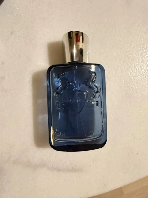 Parfym Parfums de Marly Sedley Sample 60kr/ml - Parfums de Marly Sedley är en parfym i en stilren mörkblå glasflaska med silverfärgat lock. Doften har fräscha toppnoter av citron, mynta och bergamott, blommiga hjärtnoter och en bas av träiga och varma toner som sandelträ och patchouli. 