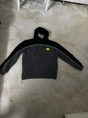 Syna world tracksuit - Säljer ett snyggt loungewear-set från Sprayground i svart och mörkgrått med neongula detaljer. Setet består av en hoodie med dragsko och matchande byxor med resårmidja och dragsko. Båda delarna har Sprayground-logga på bröst och lår. Perfekt för chill dagar hemma.