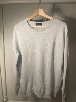 Ljusgrå tröja från Bruun & Stengade - En stilren ljusgrå tröja från Bruun & Stengade. Tröjan har rund halsringning, långa ärmar och ribbade muddar vid ärmslut och nederkant. Perfekt för en clean och enkel look, lätt att matcha med olika outfits.