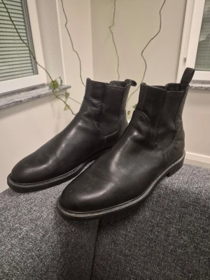 Vagabond svarta Chelsea boots i skinn 38 - Stilrena svarta Chelsea boots i äkta skinn från Vagabond med klassisk rund tå och elastiska paneler på sidorna. Perfekta för dig som gillar en tidlös och clean look. Sulan är låg och bootsen har dragflik bak för enkel påtagning.