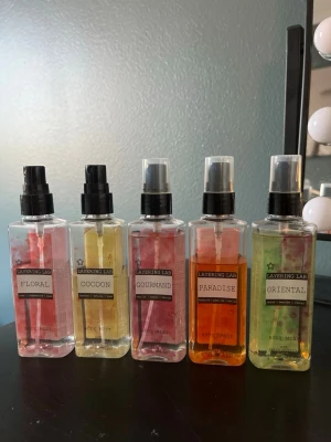 Layering Lab body mists 5-pack - Säljer ett set med fem Layering Lab body mists i dofterna Floral, Cocoon, Gourmand, Paradise och Oriental. Flaskorna är genomskinliga med svart spraykork och etiketter i olika färger. Perfekt för dig som gillar att mixa och matcha dofter.