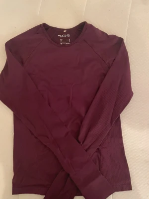Vinröd långärmad träningströja Move - Snygg vinröd långärmad träningströja från Move. Tröjan har rund halsringning och är tillverkad i ett stretchigt funktionsmaterial som passar perfekt till träning eller löpning. Enkel och stilren design utan tryck.