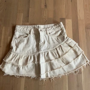 Off-white jeanskjol med asymmetriska volanger  - Så fin jeanskjol från Gina Tricot som tyvärr inte säljs längre. Den är lite off-white med asymmetriska volanger och råa kanter. Egna bilder kommer snart! 🌸😊Säljer då den tyvärr inte passar mig